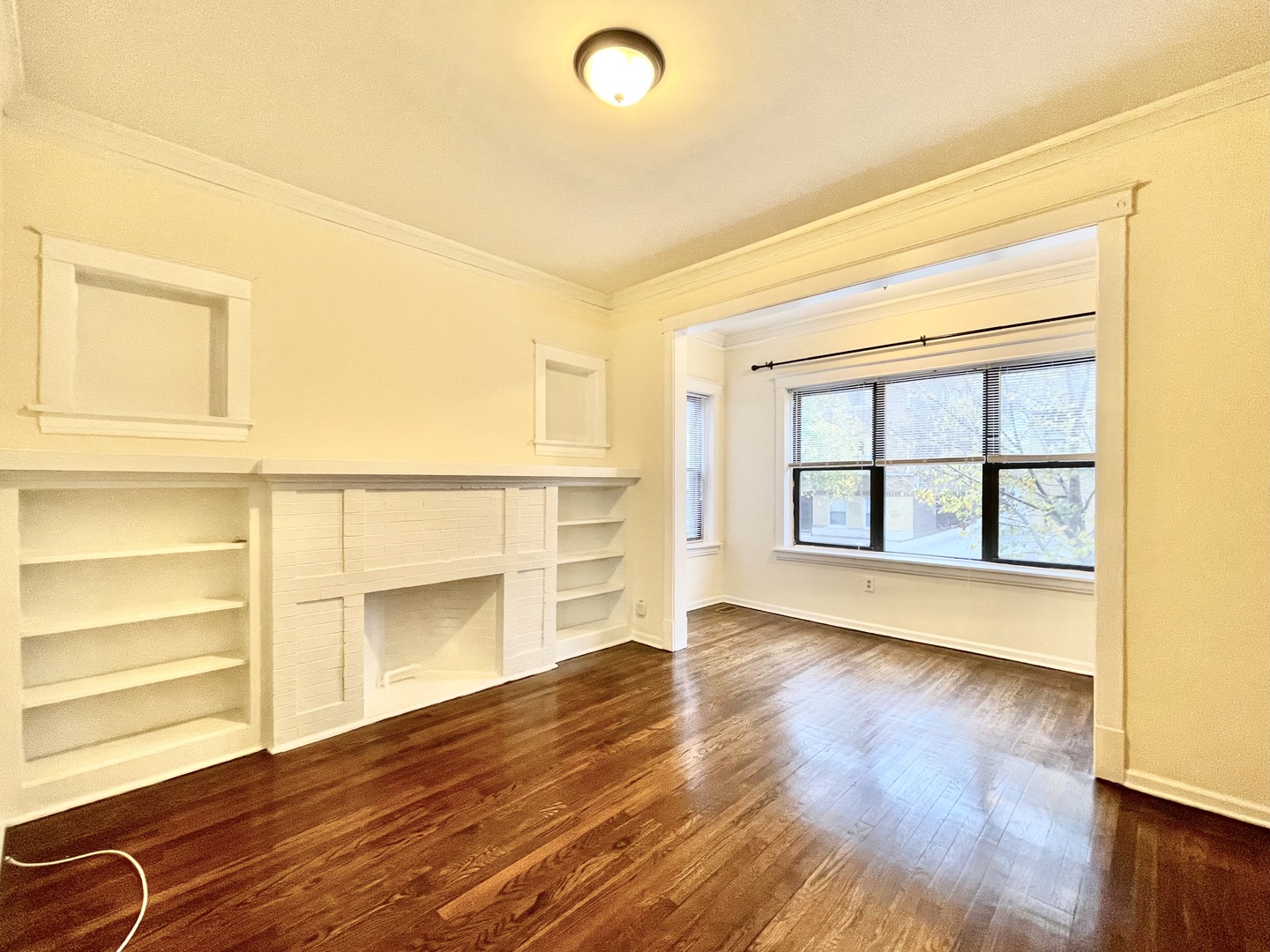 4349 North Spaulding Avenue, Unit 1 Chicago, IL 60618 - Photo 2 of 18 a view of an empty room with wooden floor and a window