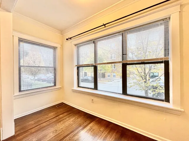 a view of an empty room with a window and wooden floor