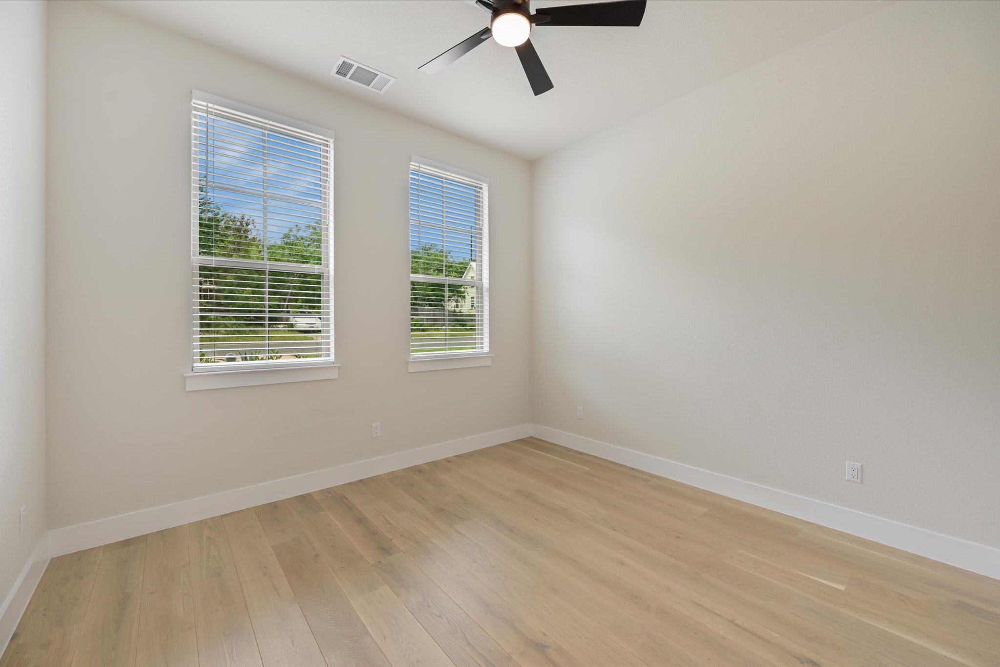 913 Presa Arriba Road Austin, TX 78733 - Photo 24 of 30 Well-lit interior space with sleek hardwood floors and a modern ceiling fan for comfort.