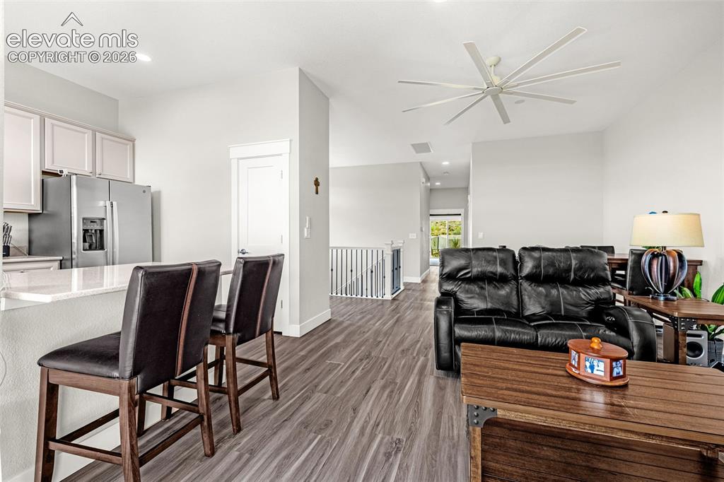 260 Eagle Summit Point, Unit 101 Colorado Springs, CO 80919 - Photo 20 of 33 LVP flooring, living room with gas fireplace, kitchen, and a balcony