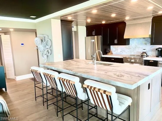 a kitchen with stainless steel appliances kitchen island granite countertop a table chairs in it and wooden floors