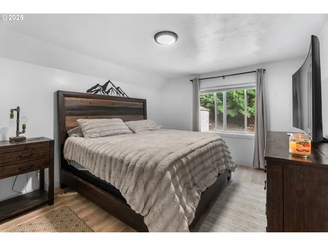 a bedroom with a bed and a flat tv screen on a dresser