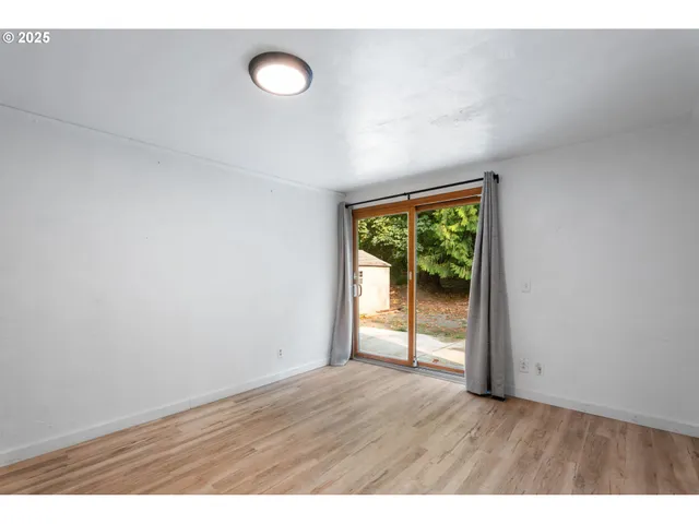 a view of an empty room with wooden floor and window