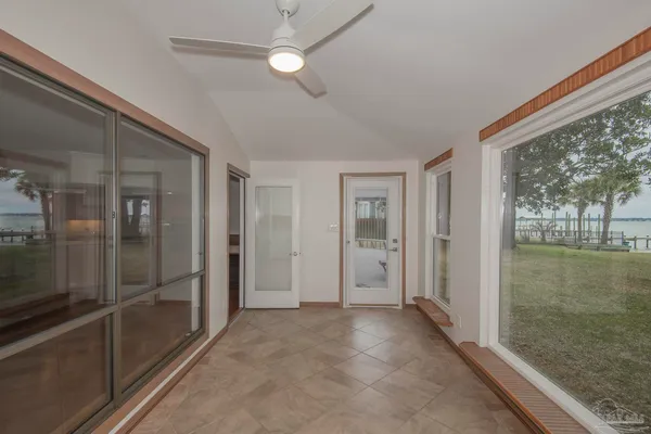 an empty room with wooden floor fan and windows