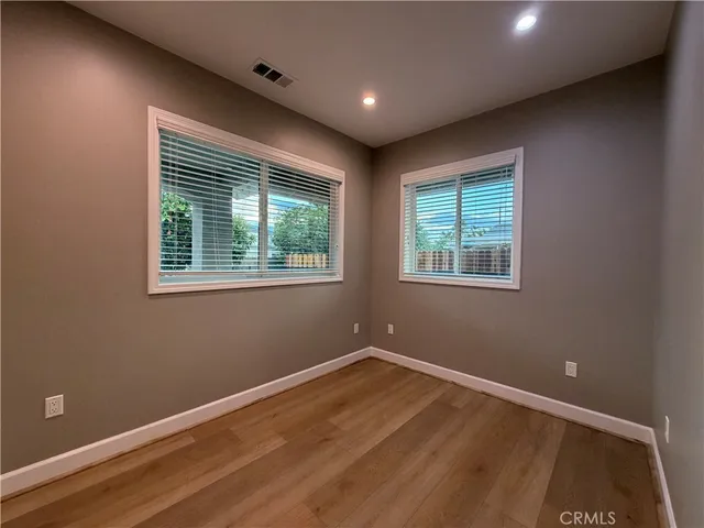a view of empty room with wooden floor and fan