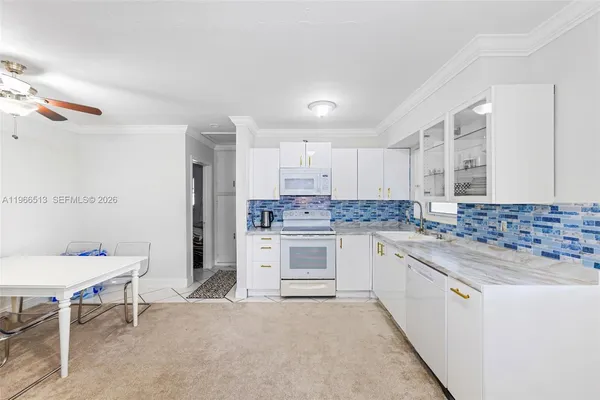 a kitchen with granite countertop white cabinets and white appliances