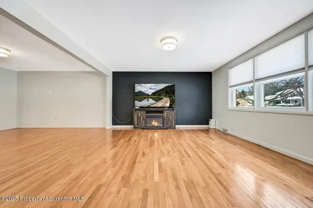 a view of empty room with wooden floor and flat screen tv