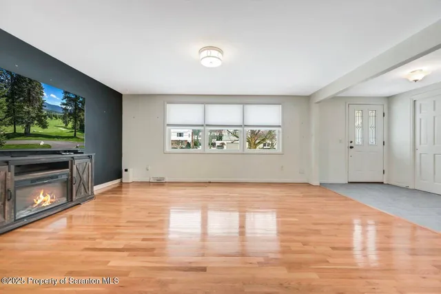 a big room with wooden floor and kitchen view