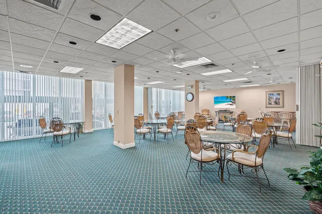 a room with lots of tables a large window and chairs