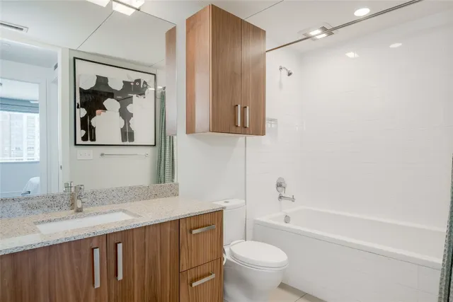 a bathroom with a granite countertop sink a toilet and a bathtub