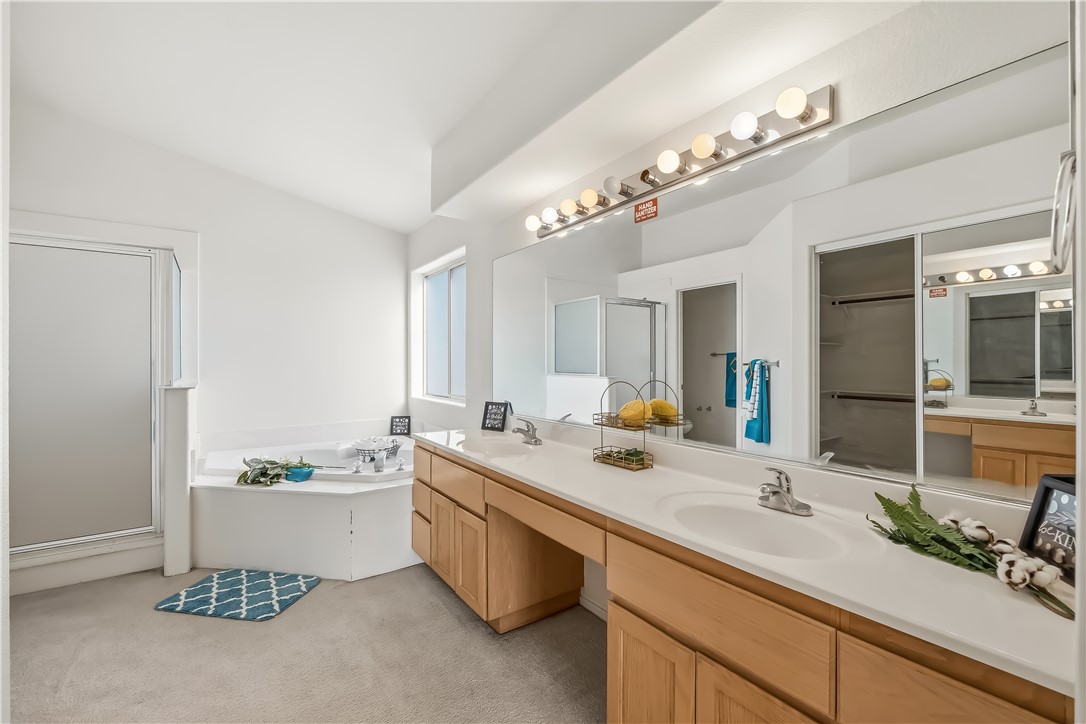 2853 Winchester Road Bullhead City, AZ 86442 - Photo 23 of 40 Bathroom featuring a dual vanity with light wood cabinetry, a large corner soaking tub, a stand-alone shower with a frosted glass door, an expansive wall mirror, and overhead vanity lighting