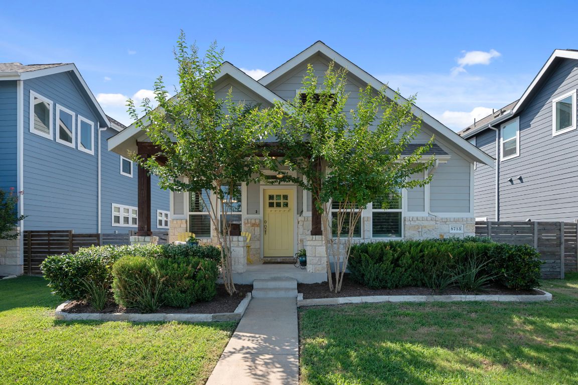 a front view of a house with a yard and potted plants