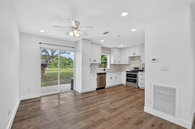 a kitchen with kitchen island white cabinets and stainless steel appliances