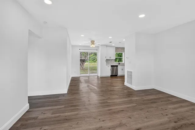 a view of an empty room with a window and wooden floor