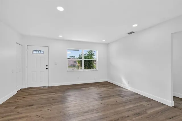 a view of a big room with wooden floor and windows