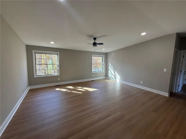 an empty room with wooden floor and windows