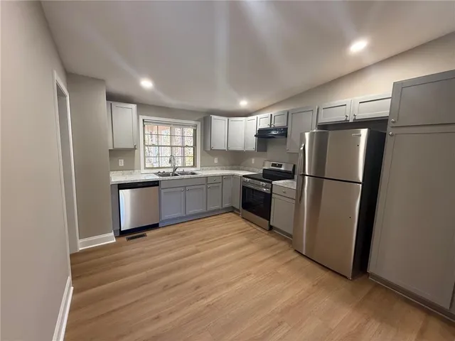 a kitchen with granite countertop stainless steel appliances a refrigerator a sink a window and cabinets