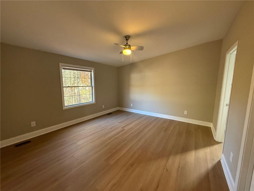 3726 Bolding Road Flowery Branch, GA 30542 - Photo 5 of 8 an empty room with wooden floor ceiling fan and windows