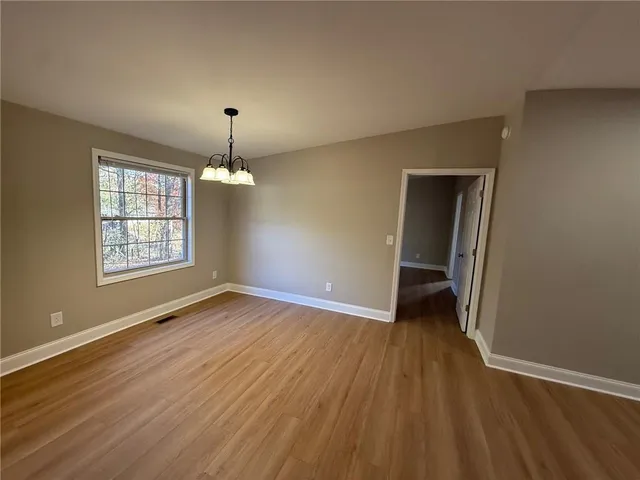an empty room with wooden floor cabinet and windows