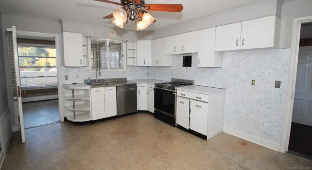 a kitchen with stainless steel appliances a sink a stove a refrigerator cabinets and a window