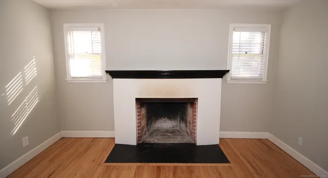 an empty room with wooden floor a fireplace and windows