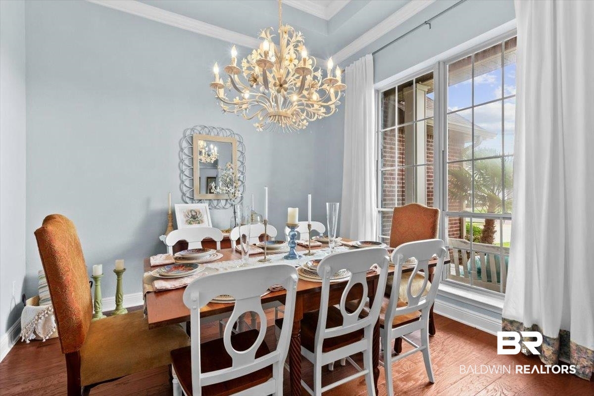 7056 Rocky Rd Loop Gulf Shores, AL 36542 - Photo 15 of 41 Dining room with healthy amount of natural light, dark wood-style flooring, crown molding, and a chandelier