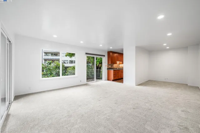 a view of an empty room with a window and a kitchen