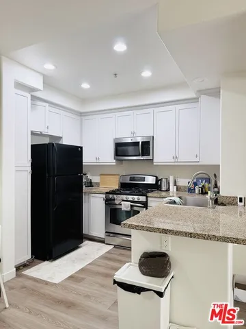 a kitchen with granite countertop a refrigerator stove top oven and sink