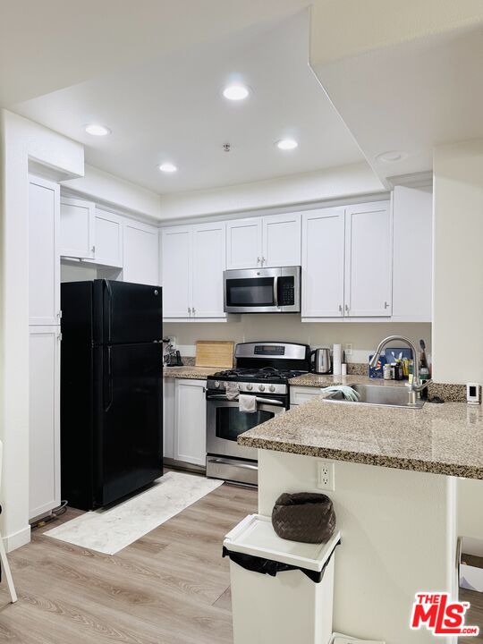 a kitchen with granite countertop a refrigerator stove top oven and sink