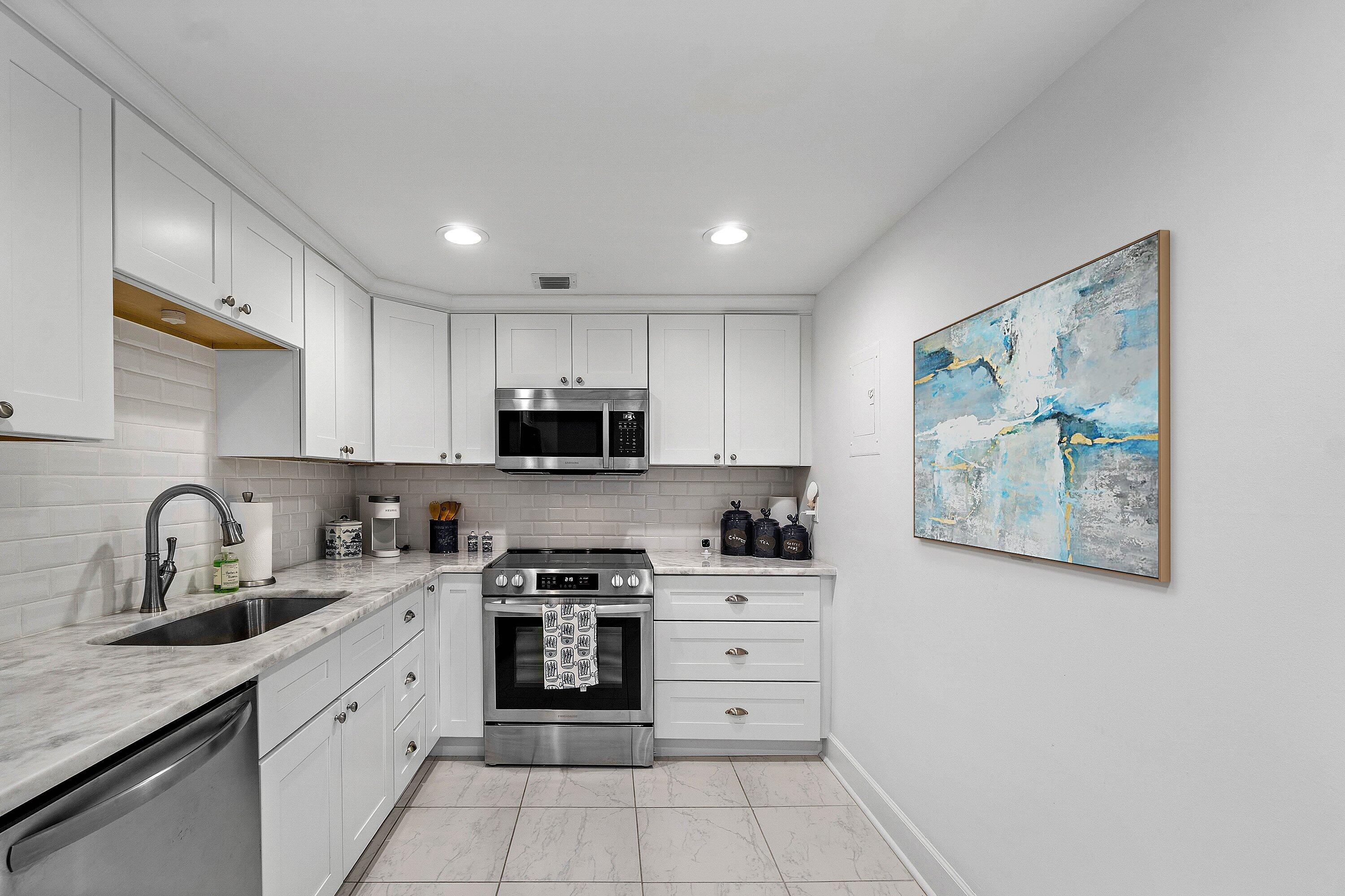 3800 Washington Road, Unit 904 West Palm Beach, FL 33405 - Photo 7 of 27 a kitchen with stainless steel appliances granite countertop a stove a sink and a microwave