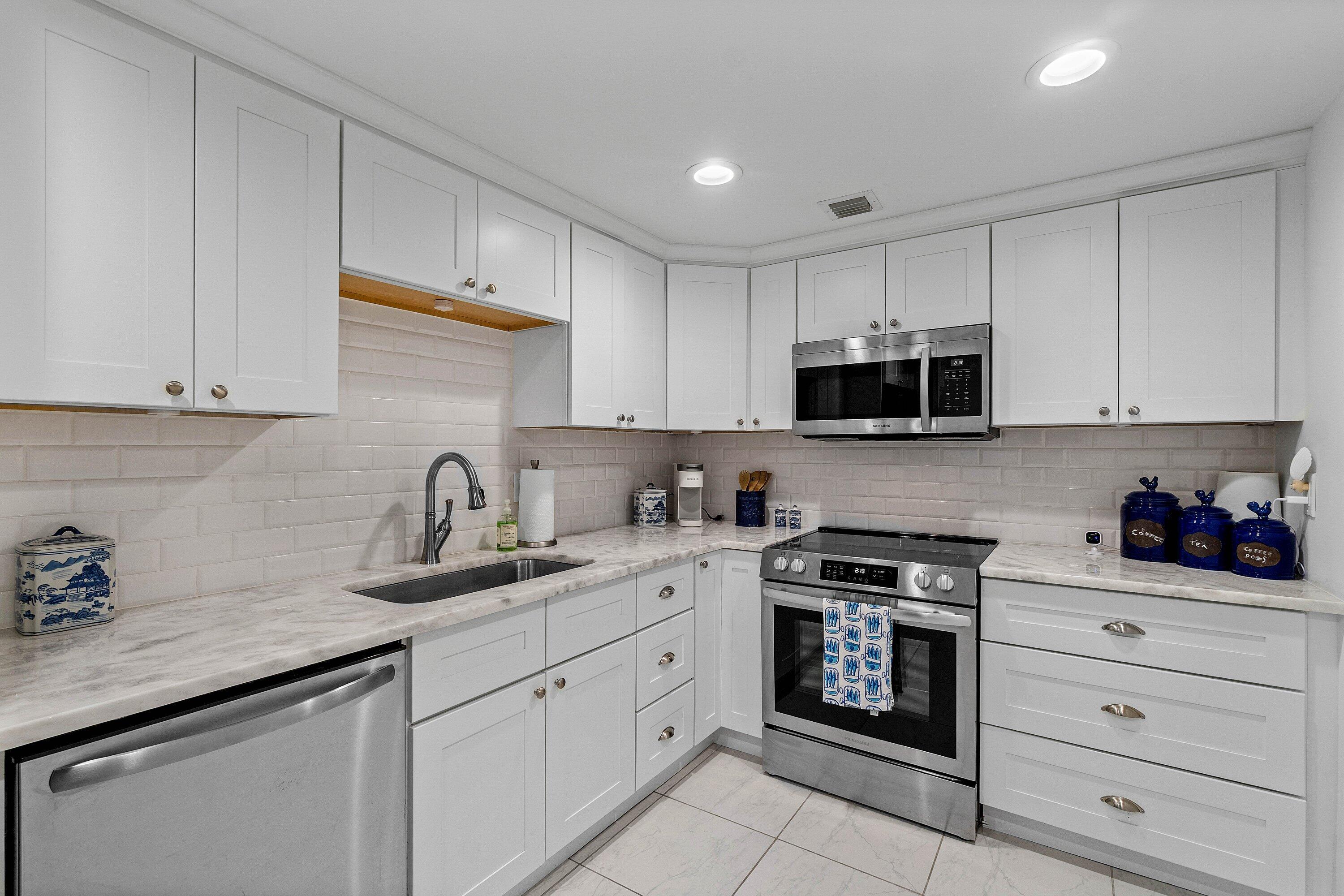 3800 Washington Road, Unit 904 West Palm Beach, FL 33405 - Photo 8 of 27 a kitchen with granite countertop white cabinets stainless steel appliances and a sink
