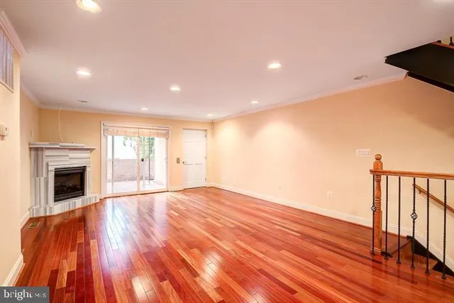 a view of an empty room with wooden floor fireplace and a window