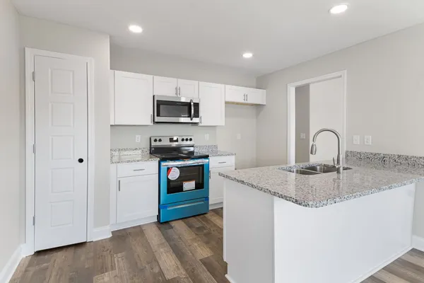 a kitchen with granite countertop a sink stove and refrigerator