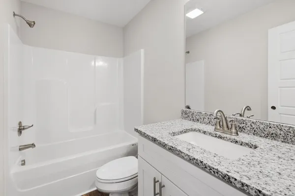 a bathroom with a granite countertop sink a toilet and bathtub