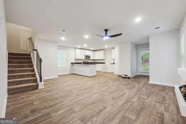a view of an empty room with wooden floor and a kitchen