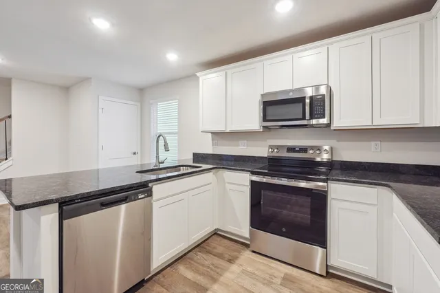 a kitchen with granite countertop white cabinets and stainless steel appliances