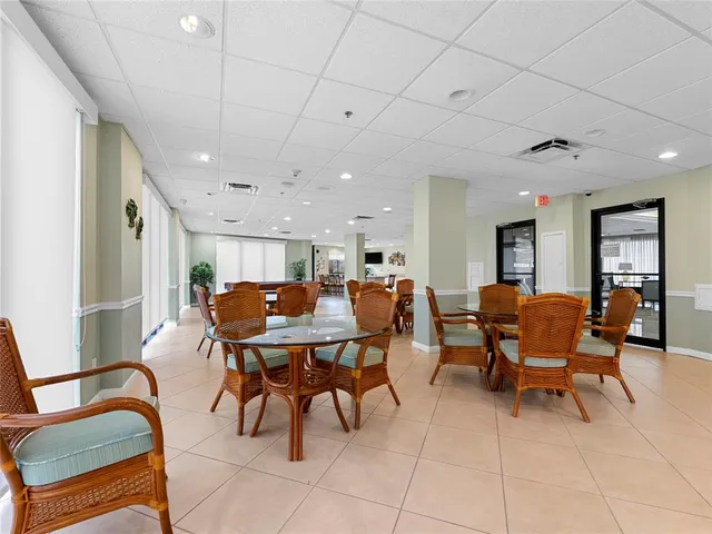 a dining hall with stainless steel appliances a dining table and chairs with the view of kitchen