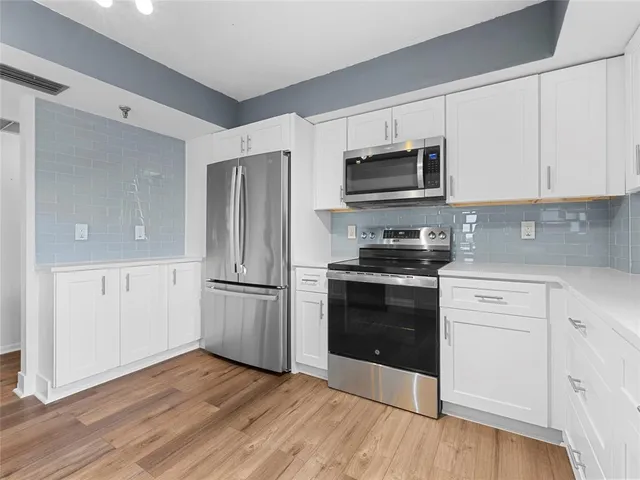 a kitchen with granite countertop a refrigerator stove and white cabinets