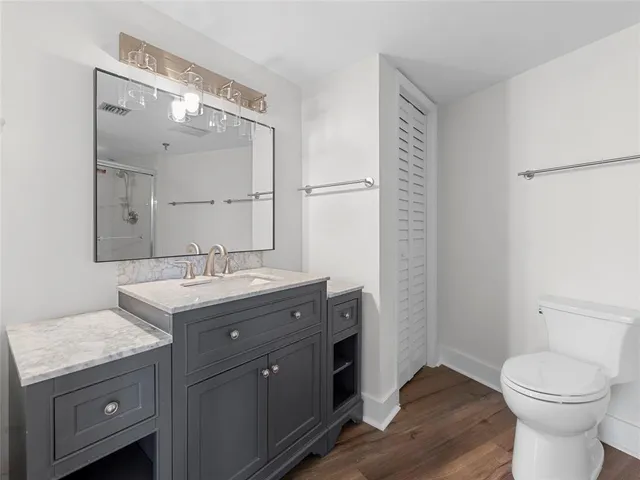 a bathroom with a granite countertop sink toilet and mirror