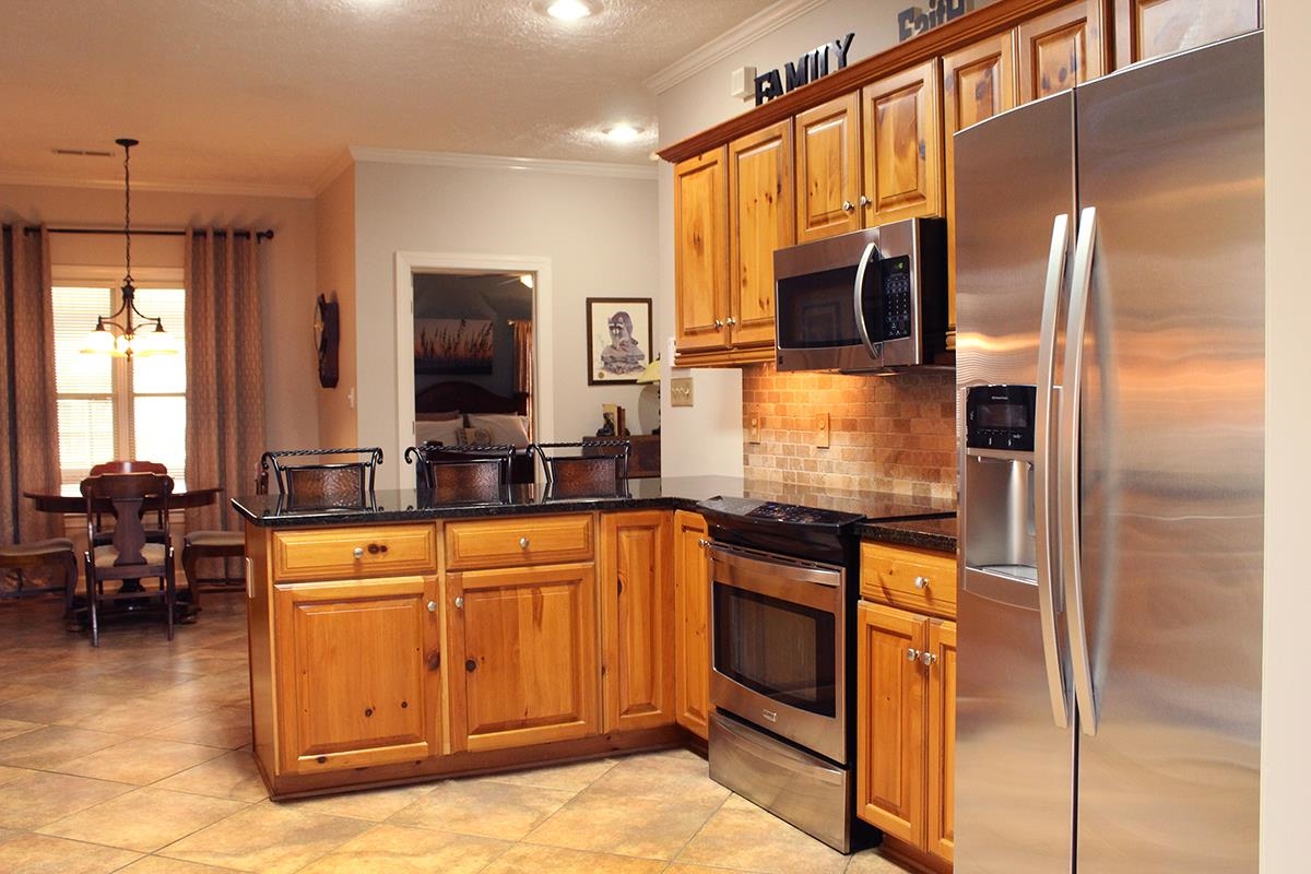 175 Windale Drive Jackson, TN 38305 - Photo 20 of 25 Kitchen with stainless steel appliances, a peninsula, wood finish cabinets, ornamental molding, and dark stone countertops