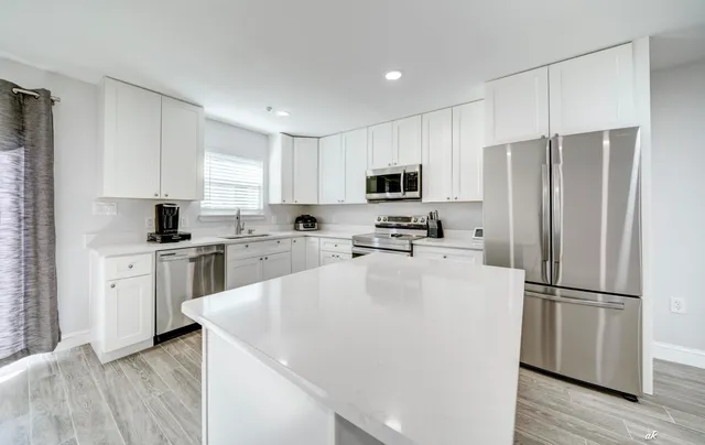 a kitchen with kitchen island a white cabinets and stainless steel appliances