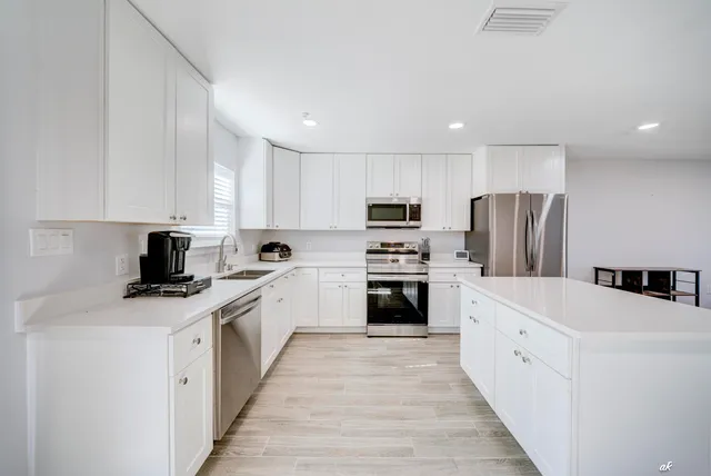 a kitchen with white cabinets and stainless steel appliances