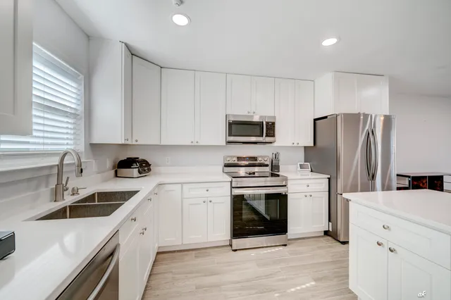 a kitchen with cabinets stainless steel appliances a sink and wooden floor