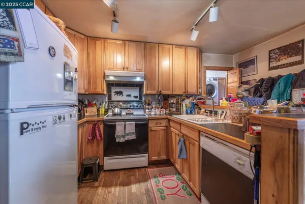 a kitchen with stainless steel appliances a sink a stove a refrigerator cabinets and a dining table