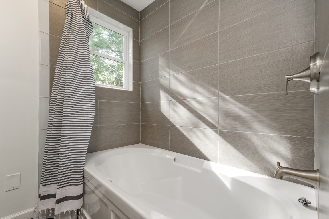 5323 Downs Drive Austin, TX 78721 - Photo 14 of 28 a bathroom with a white bath tub and a window