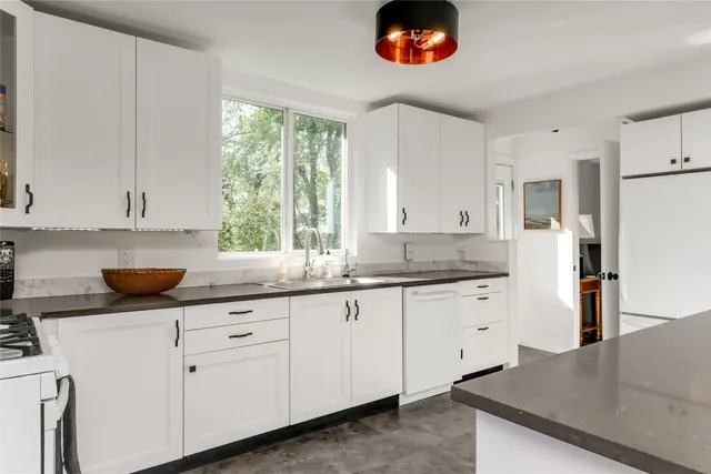a kitchen with granite countertop white cabinets and a sink
