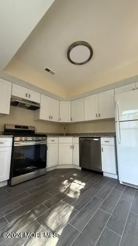 a kitchen with a stove and white cabinet