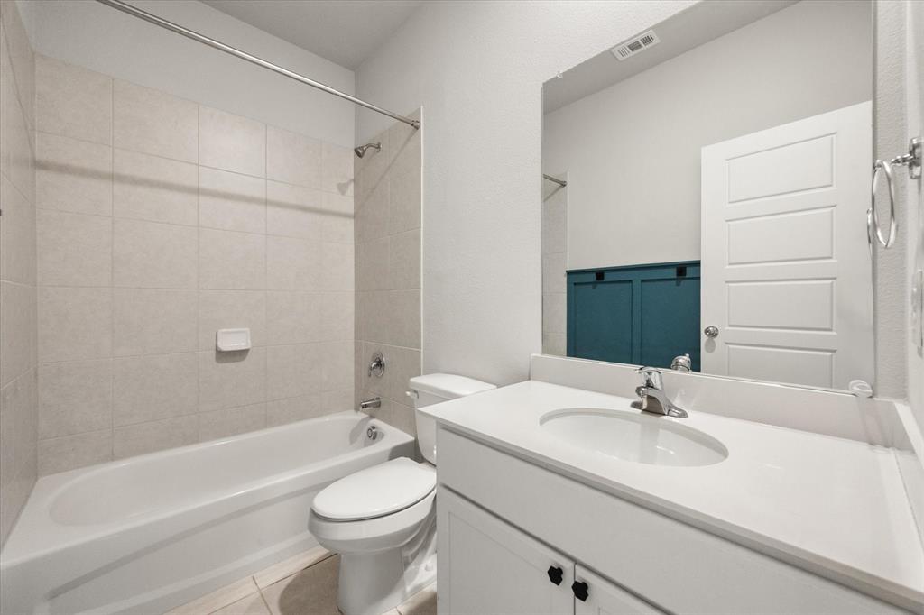 6910 Prairieside Trail Venus, TX 76084 - Photo 26 of 40 Full bathroom downstairs featuring a white bathtub with tiled surround, a vanity with a white countertop and integrated sink,