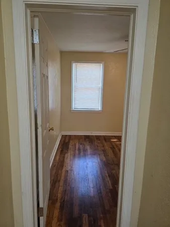 a view of a hallway with wooden floor and a window
