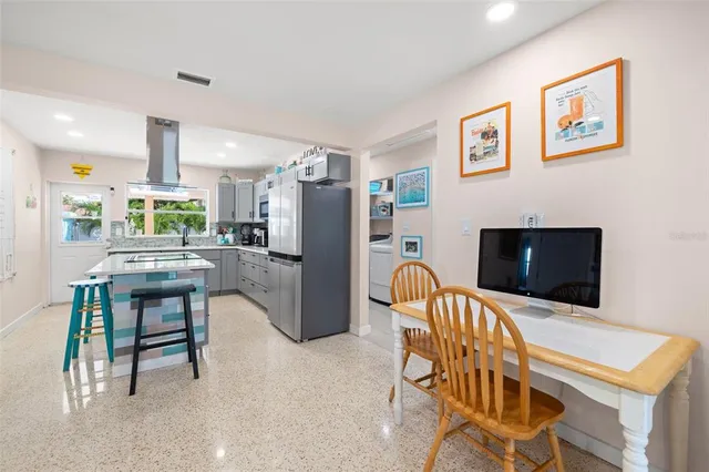 a kitchen with stainless steel appliances kitchen island granite countertop a refrigerator and a dining table